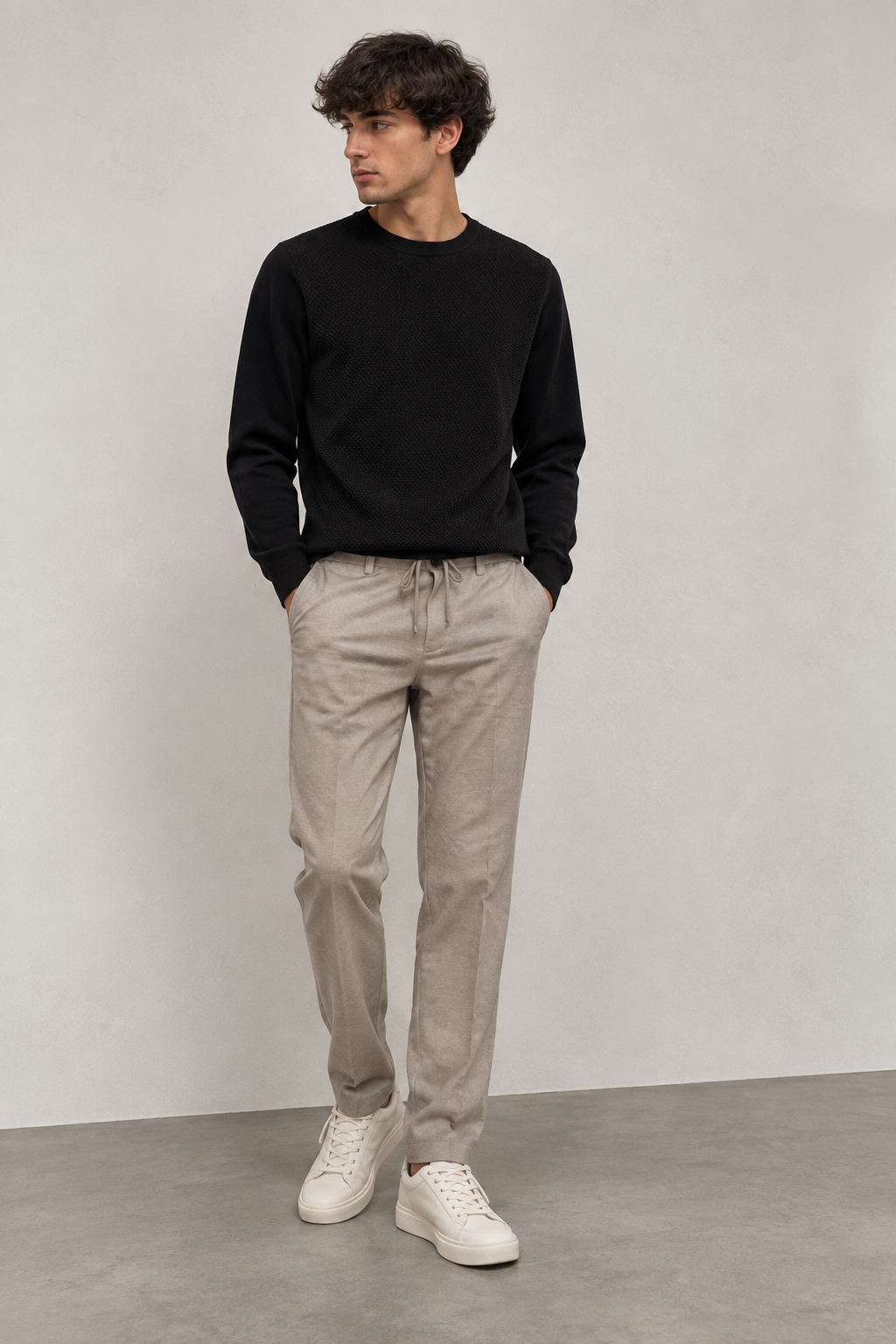 Uomo con maglione nero e pantalone beige