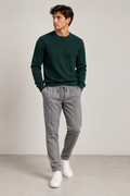 Uomo con maglione verde e pantalone grigio